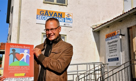 Bergslagskyrkans pastor Andreas Collin sätter upp Världens Barns affisch vid Gåvan, för att tala om vart pengarna går på lördag.